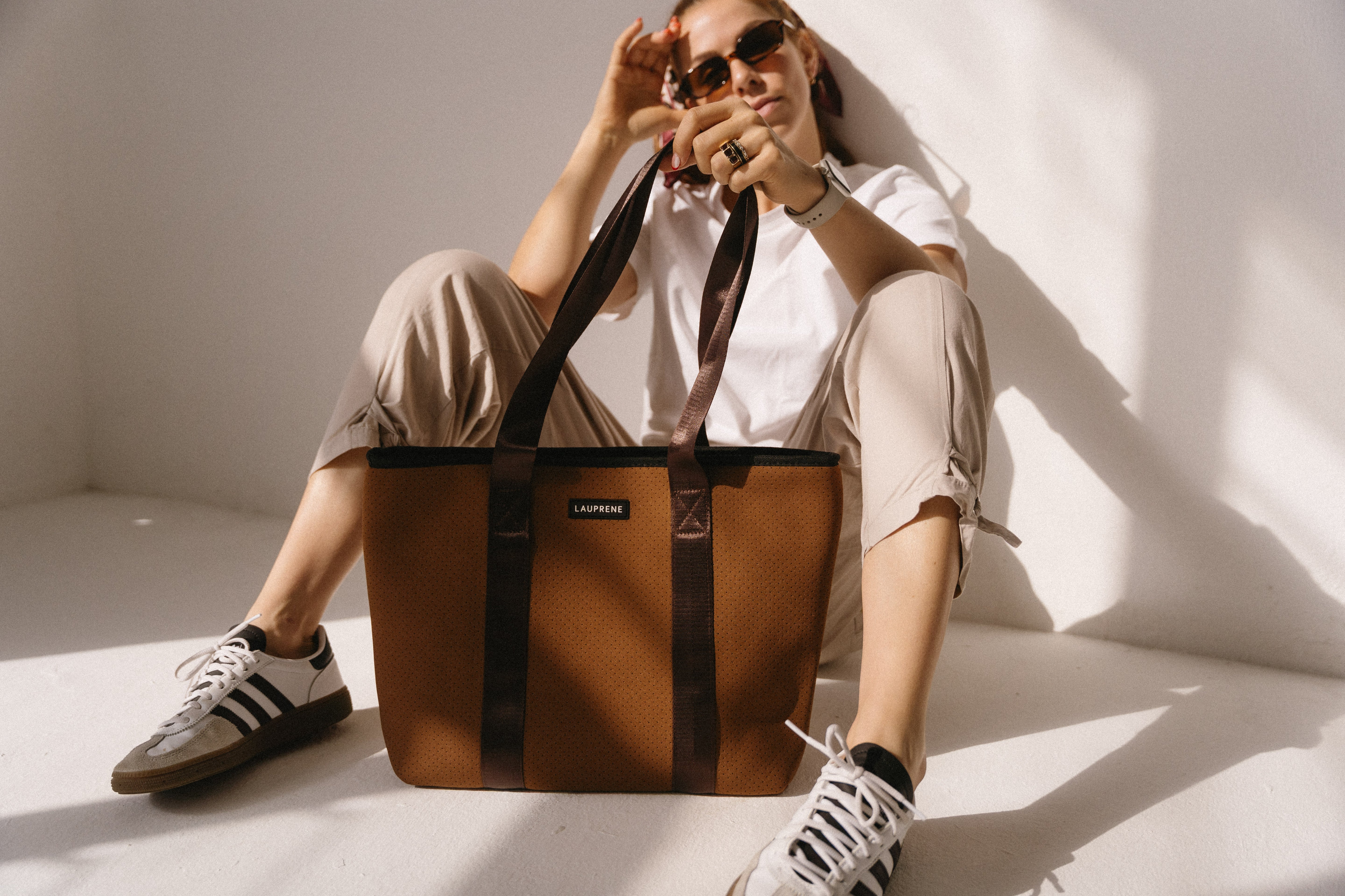 Person holding a brown bag with a visible brand logo against a white background