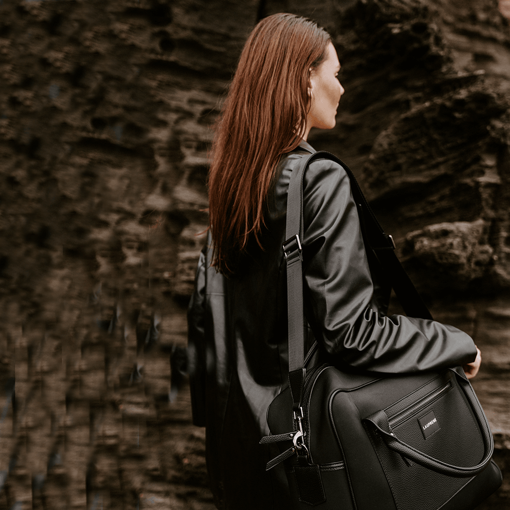 Woman with long red hair carrying a black Lauprene Supanova duffel bag.