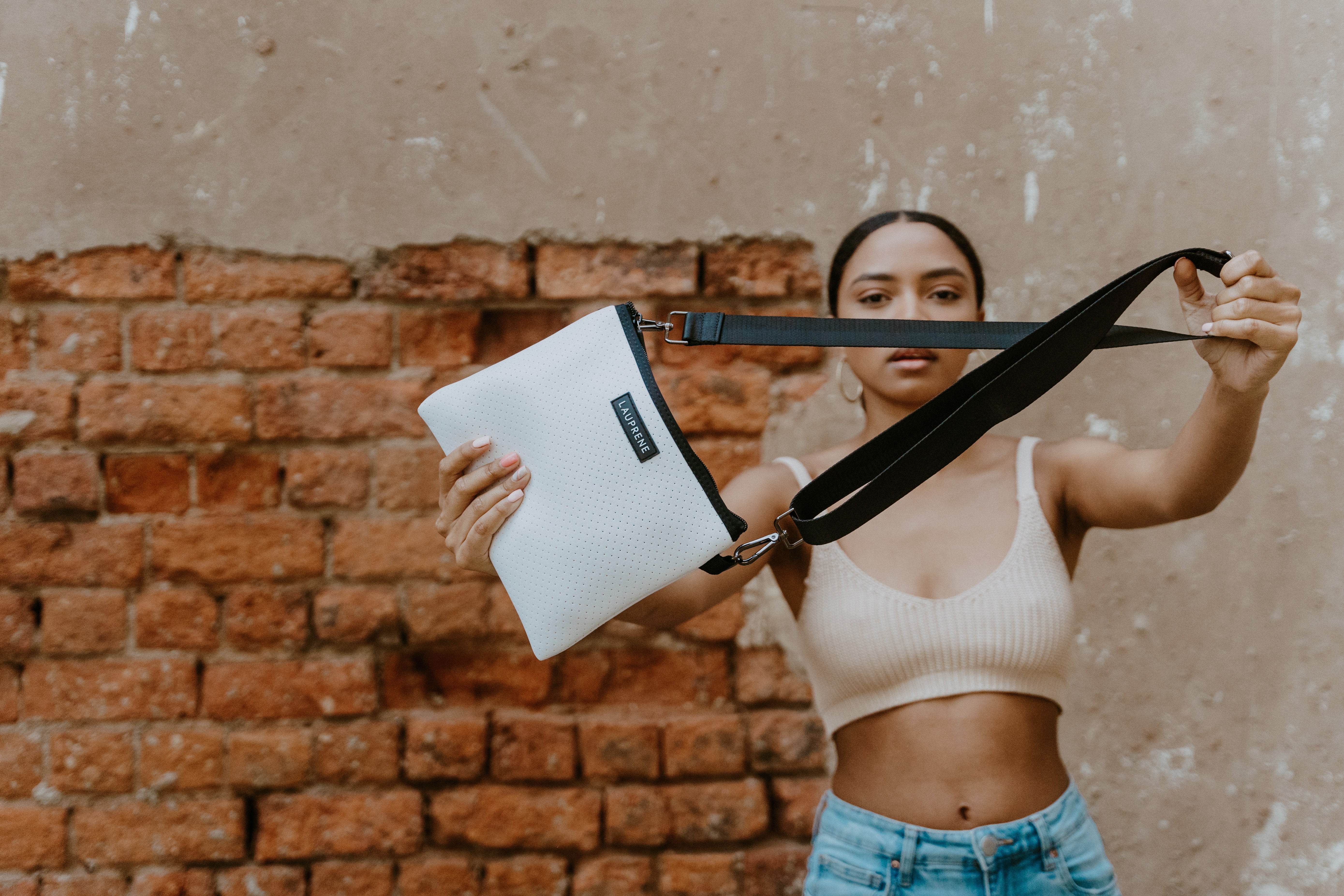 Woman holding a white messenger with black strap